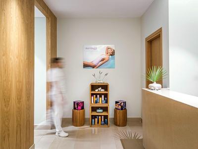 Modern hotel lobby with wooden paneling, small bookshelf, and plants on the counter