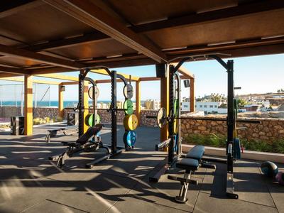 Palestra luminosa con attrezzi e vista mare attraverso grandi finestre