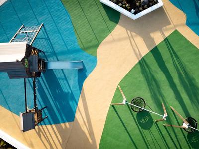 Bird's-eye view of a pool with lounge chairs and green lawn next to a sandy path.