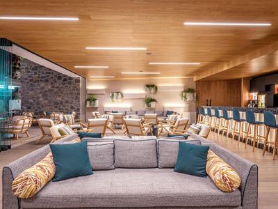 Moderner Hotel-Loungebereich mit gemütlichen Sofas, Barhockern und warmem Holzdekor.