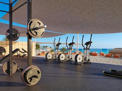Freiluft-Fitnessstudio mit Gewichthebern und Fahrrädern mit Blick auf das Meer und klare Himmel.