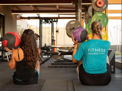 Zwei Frauen beim Fitness mit Medizinbällen in einem hellen Fitnessstudio.