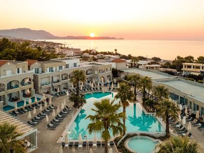 Hotel mit Pool und Palmen am Meer, Sonnenuntergang am Horizont.