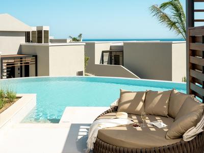 Moderner Poolbereich mit bequemer runder Liege und Blick auf das Meer.