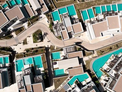 Vogelperspektive auf moderne Hotelanlage mit blauen Pools und weißen Gebäuden.