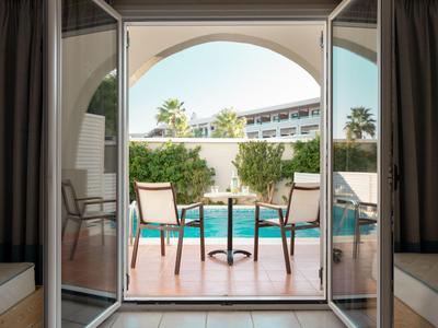 Blick auf eine Terrasse mit Stühlen und einem Pool in einem Hotel bei sonnigem Wetter.