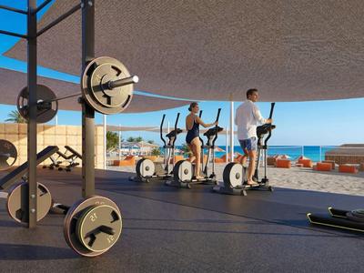Offener Fitnessbereich mit Geräten und Blick auf das Meer in einem Hotel
