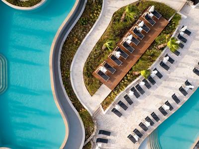 Luftaufnahme eines geschwungenen Pools mit Sonnenliegen und einem überdachten Sitzbereich.