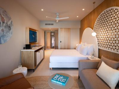Helles Hotelzimmer mit Doppelbett, Sofa, Fernseher und modernem Dekor.