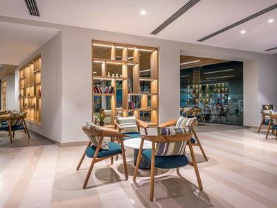 Modern eingerichteter Loungebereich mit Holzmöbeln und beleuchtetem Bücherregal in einem Hotel.