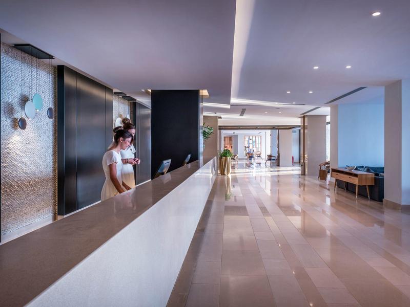 Modern hotel lobby reception with receptionist and spacious, bright corridor.