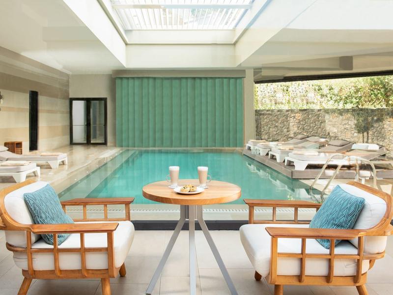 Modern indoor pool area with seating and natural light from the skylight.