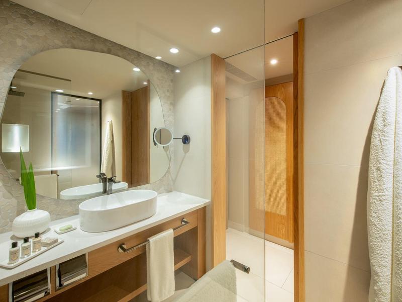Modern bathroom with large mirror, sink on wooden countertop, and towel hanging on wall.