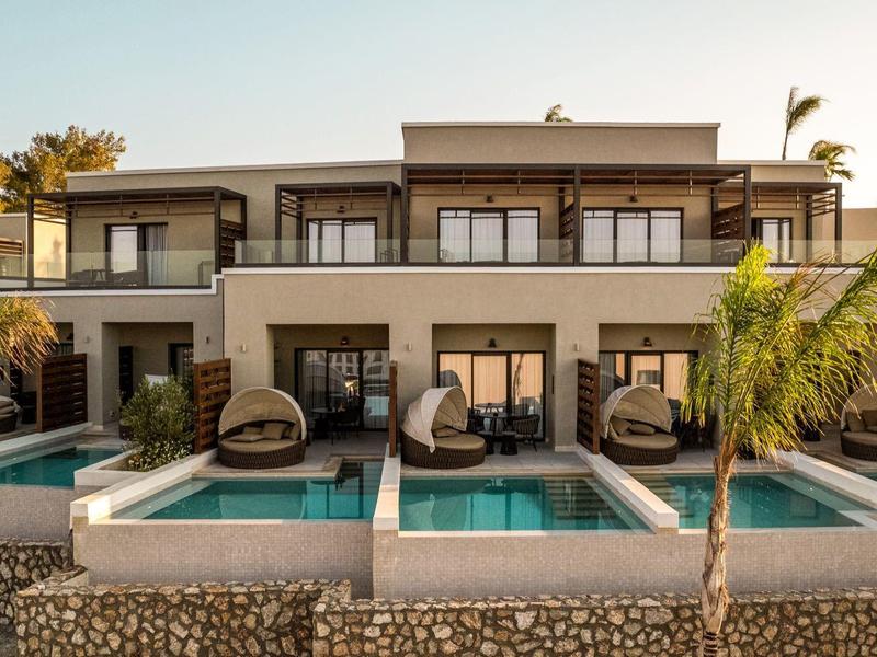 Modern hotel with three private pools and terraces surrounded by palm trees at sunset.