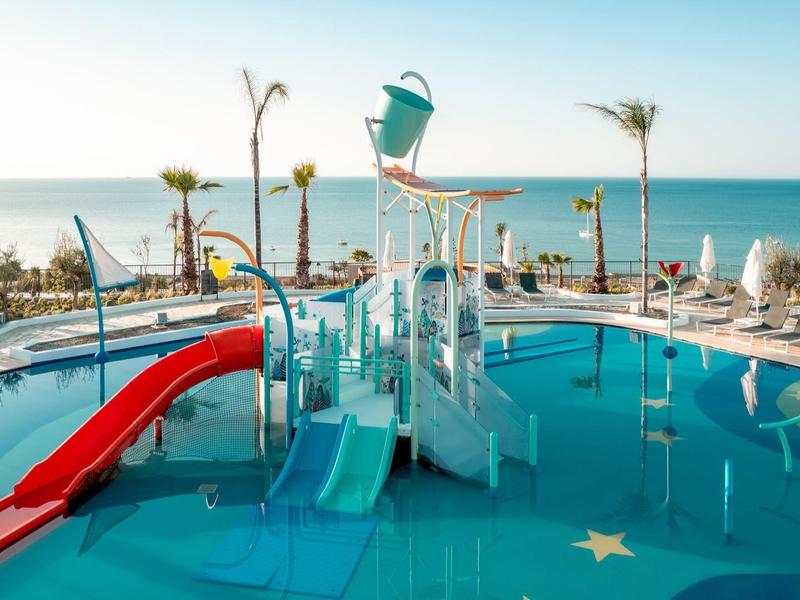 Water park with colorful slides and ocean view in the background.