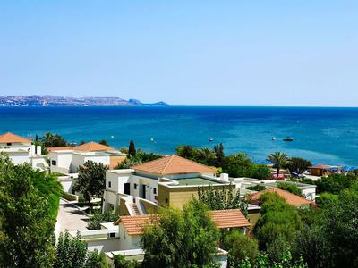 Blick auf ein Küstenhotel mit roten Dächern und blauem Meer im Hintergrund.