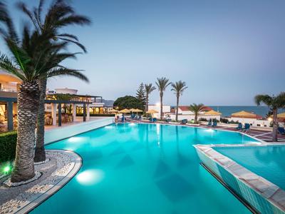 Moderner Hotelpool bei Sonnenuntergang mit Palmen und Meerblick.