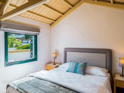 Schlafzimmer mit großem Bett, weißen Wänden und offenem Fenster mit Blick auf grüne Landschaft.