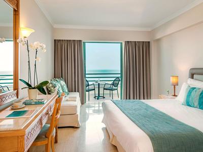 Modernes Hotelzimmer mit Doppelbett, Schreibtisch und Balkon mit Meerblick.