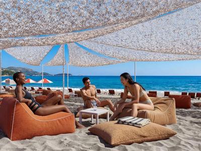 Strand mit bequemen Sitzkissen, sonnengeschütztem Bereich und Blick aufs blaue Meer.
