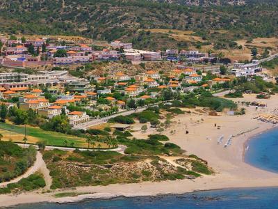 A coastal town with sandy beaches, clear blue water, and numerous buildings near the shore.