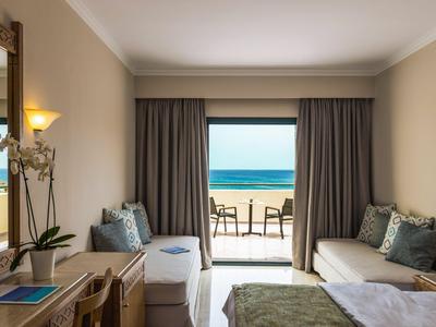 Camera d'hotel con letto matrimoniale, zona salotto e vista sulla terrazza e il mare.