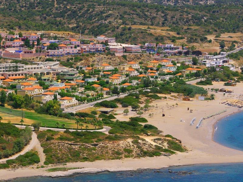 A coastal town with sandy beaches, clear blue water, and numerous buildings near the shore.