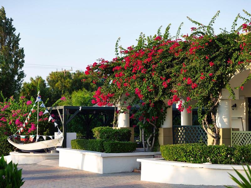 Outdoor patio with hammock, white seating, and vibrant red flowers on pergola.