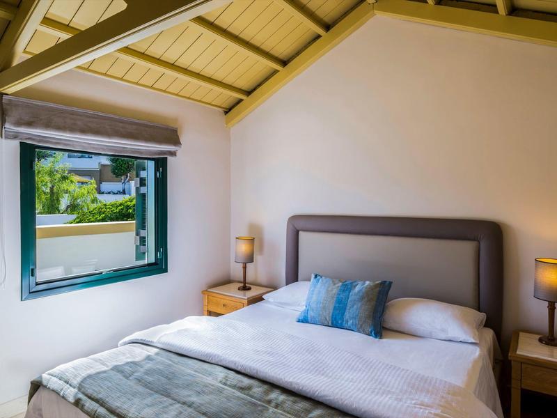 Cozy bedroom with a large bed, nightstands, lamps, and a window showing green outdoors.