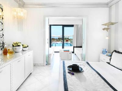 Camera d'hotel elegante con letto matrimoniale e vista mare attraverso ampie finestre.