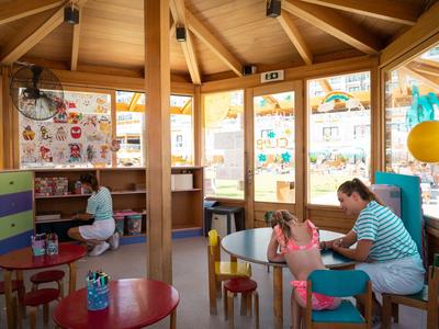 Komfortabler Hotel-Kinderspielbereich mit Holzsäulen, bunten Tischen und Stühlen, Kinderbespaßung.