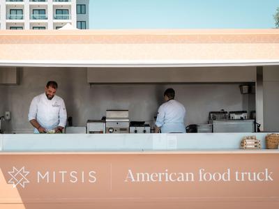 Moderner Foodtruck mit zwei Köchen in weißen Hemden vor einem Hotelgebäude.