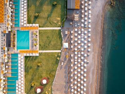 Drohnenansicht eines Hotels mit Pool, Liegestühlen und direktem Zugang zum Strand.