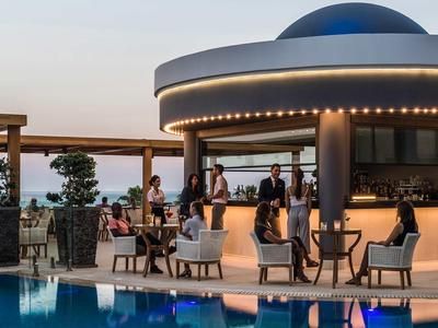 Bar serale con area salotto accanto a una piscina in un hotel moderno.