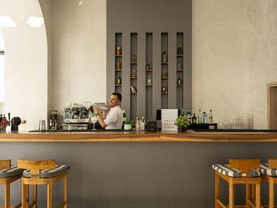 Moderner Hotelbarbereich mit hölzernen Barhockern, hellem Tresen und Barkeeper hinter der Theke.