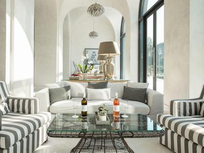 Helles Wohnzimmer mit gestreiften Sesseln, Glas-Couchtisch und Blick ins Freie.