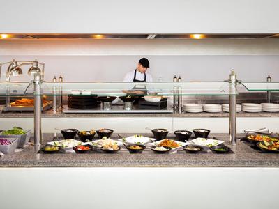 Buffet mit verschiedenen Speisen und Koch im Hintergrund.