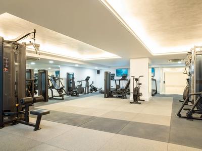 Heller Fitnessraum mit modernen Geräten und Gummiboden im Hotel.