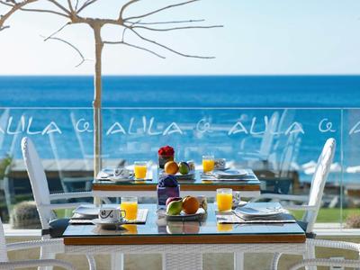 Tavolo per la colazione con succo d'arancia, caffè e croissant su balcone con vista mare.