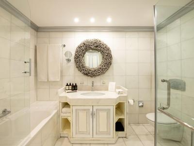 Helles Badezimmer mit Badewanne, Waschbecken, Spiegel und Dusche im Hotelzimmer.