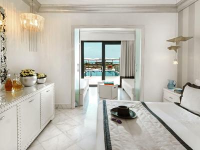 Elegantes Hotelzimmer mit Bett, modernen Möbeln und Terrasse mit Meerblick.