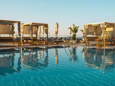 Luxuriöse Poolbetten mit Vorhängen am klaren blauen Pool unter klarem Himmel.