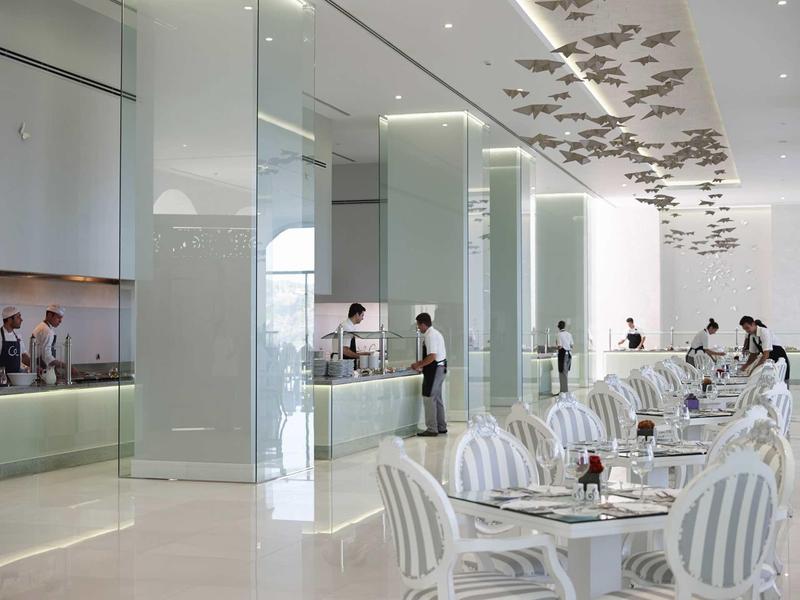 Sala da pranzo luminoso dell'hotel con sedie a righe, tavoli e design moderno.