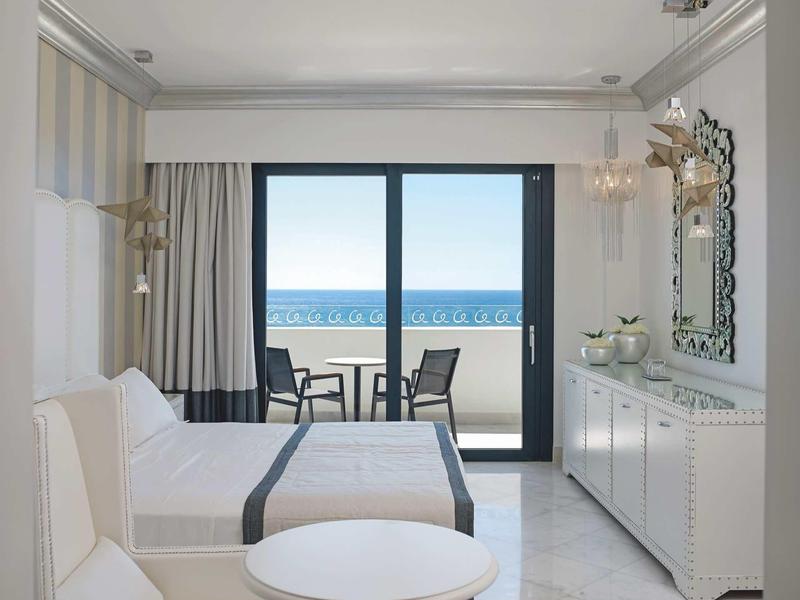 Camera d'hotel luminosa con letto matrimoniale, balcone e vista sul mare.