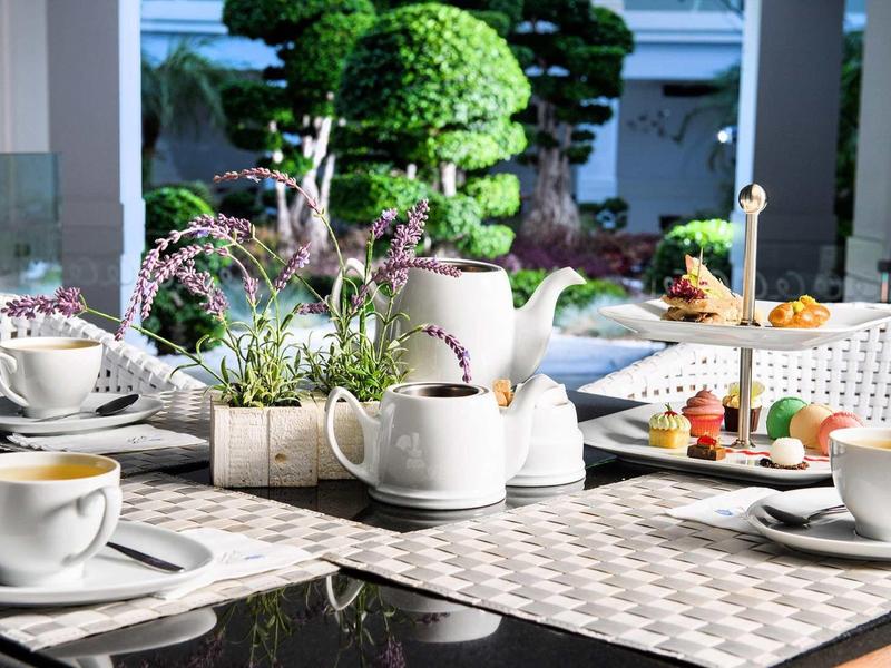 Tavolo con teiera, tazze e pasticcini, giardino sullo sfondo