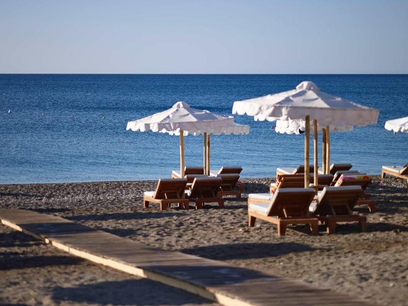 Sdraio vuote e ombrelloni sulla spiaggia tranquilla sotto un cielo sereno