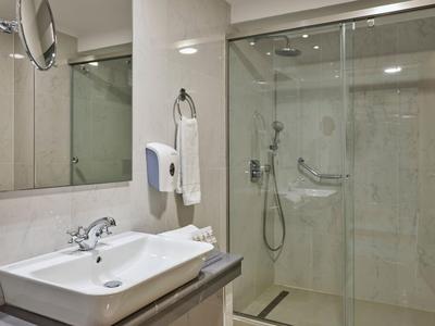 Bagno luminoso con lavabo e cabina doccia con porte scorrevoli in vetro.