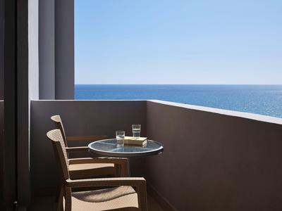 Balcone con tavolo, sedia e vista sul mare azzurro in una giornata di sole.