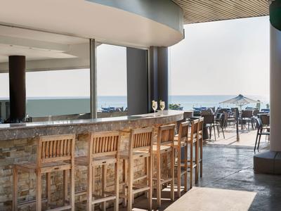 Area bar con sgabelli in legno e vista su terrazza e mare alla luce del giorno