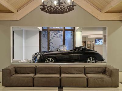 Soggiorno moderno con divano marrone e parete a specchio che riflette un'auto.